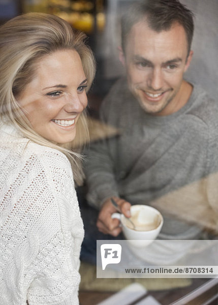 Glückliches Paar  das aus dem Caféfenster schaut und Kaffee trinkt.