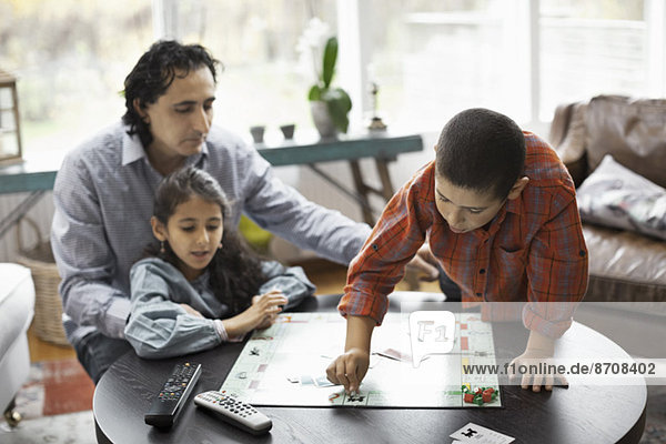 Vater und Kinder beim Monopolspiel im Wohnzimmer