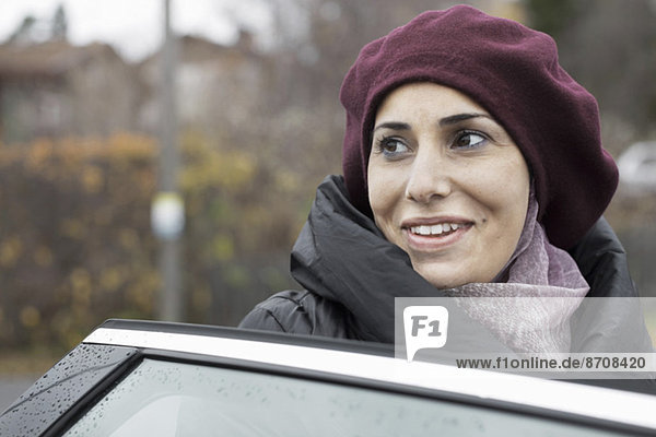 Lächelnde Frau  die durch die Autotür ins Freie blickt