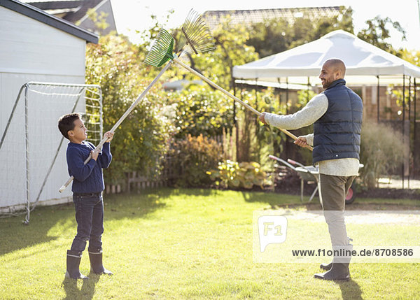 Vater und Sohn kämpfen mit Rechen im Garten