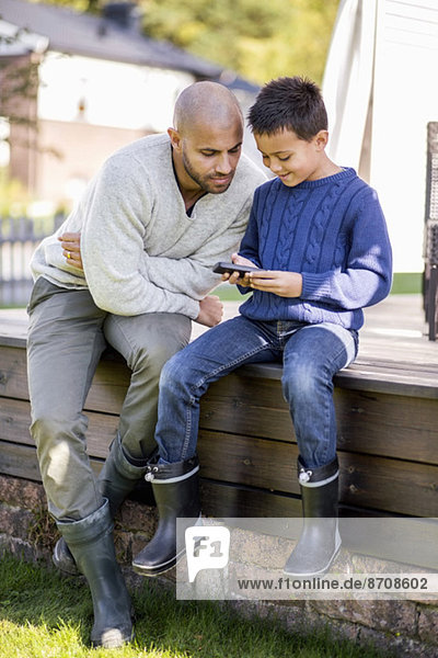 Vater und Sohn mit dem Handy auf dem Hof