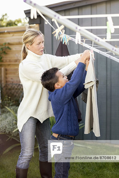 Mutter und Sohn beim Wäschetrocknen auf dem Hof