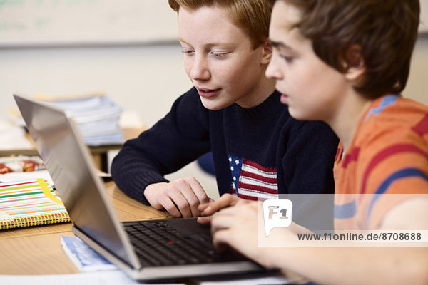 High School Jungen mit Laptop am Schreibtisch im Klassenzimmer