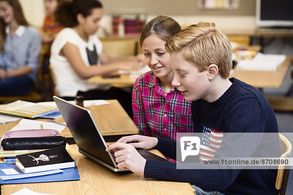 School students using laptop in classroom