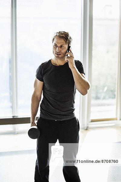 Man using mobile phone while exercising at gym