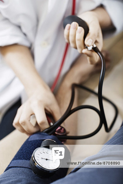 Abgeschnittenes Bild einer Ärztin  die den Blutdruck der Patientin in der Klinik nimmt