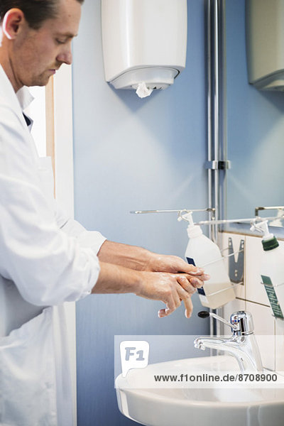 Seitenansicht des männlichen Arztes beim Händewaschen im Krankenhausbad