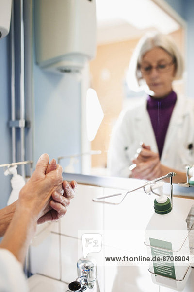 Abgeschnittenes Bild einer Oberärztin  die sich die Hände im Krankenhausbad wäscht.