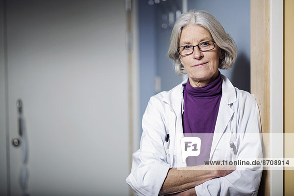 Portrait of confident senior female doctor with arms crossed in hospital