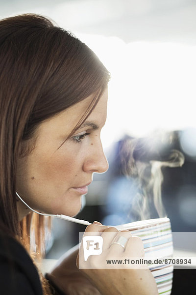 Geschäftsfrau spricht über Kopfhörer beim Kaffee im Büro