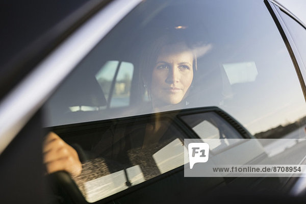 Geschäftsfrau beim Autofahren durchs Fenster schauen