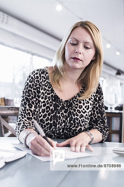 Businesswoman signing document at restaurant table
