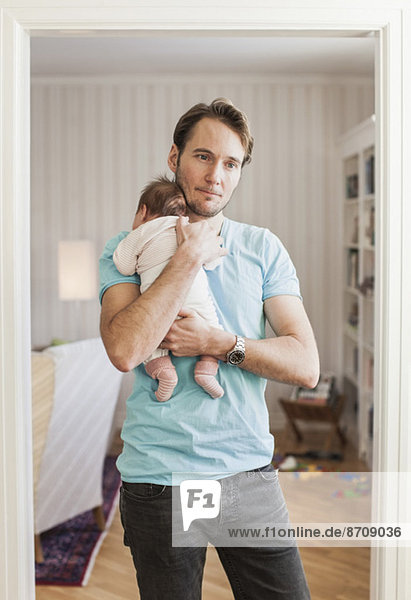 Nachdenklicher Mann mit Baby vor der Tür