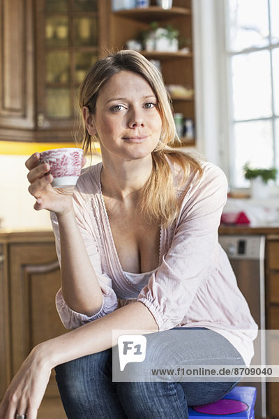 Portrait of woman holding coffee cup in kitchen