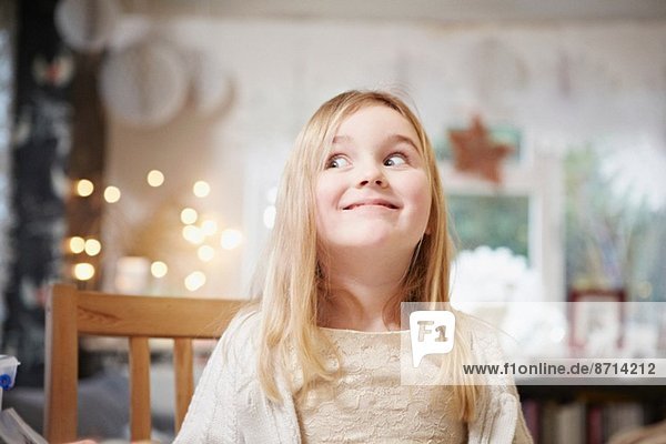 Portrait of young girl in kitchen pulling a face