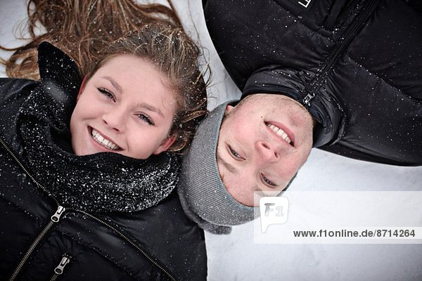 Porträt eines jungen Mädchens und ihres Bruders im Schnee liegend