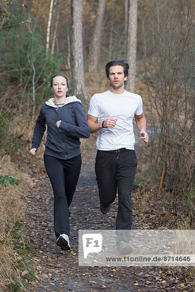 Couple running through forest