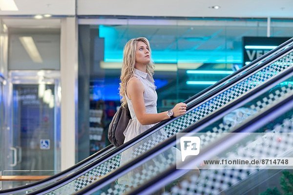 Junge Frau auf der Rolltreppe im Einkaufszentrum