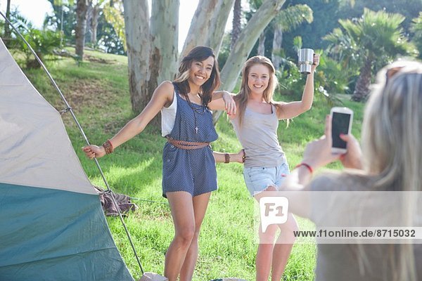 Drei junge Freundinnen beim Fotografieren auf dem Smartphone