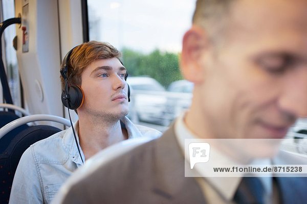 Young man listening to headphones on train