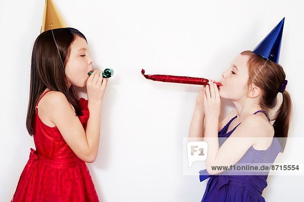 Porträt von zwei Mädchen  die Partybläser blasen