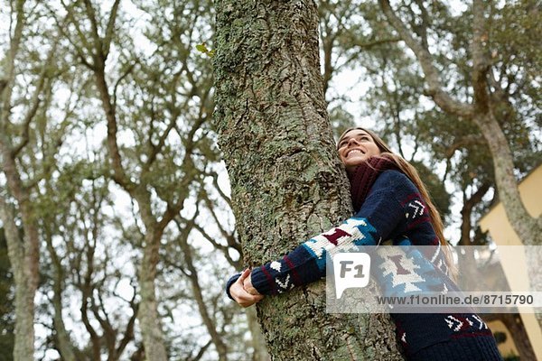 Junge Frau umarmt Baum im Wald