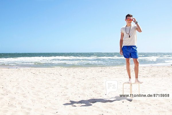 Junger Mann auf dem Hocker am Strand  Port Melbourne  Melbourne  Australien