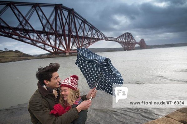 Ein junges Paar posiert vor der Forth Rail Bridge in Queensferry  nahe Edinburgh  Schottland.