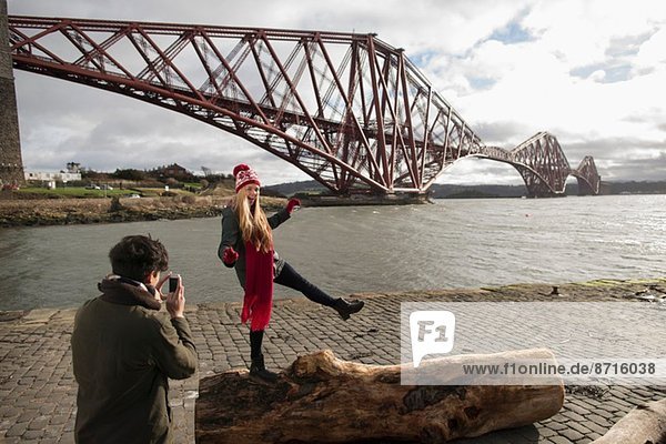 Ein junges Paar posiert vor der Forth Rail Bridge in Queensferry  nahe Edinburgh  Schottland.