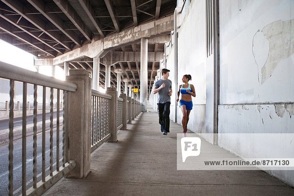 Junges Paar läuft auf der Stadtbrücke