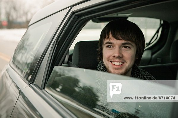 Young man looking out of car window