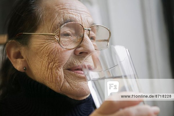 Seniorin mit einem Glas Trinkwasser