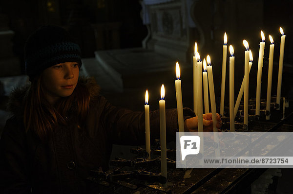 Girl lighting a votive candle  San Zaccaria Church  San Marco district  Venice  Veneto  Italy