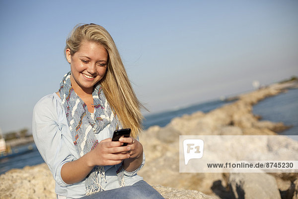 Vereinigte Staaten von Amerika  USA  Felsbrocken  sitzend  Frau  Kurznachricht  Strand  Telefon  jung  Handy  Florida