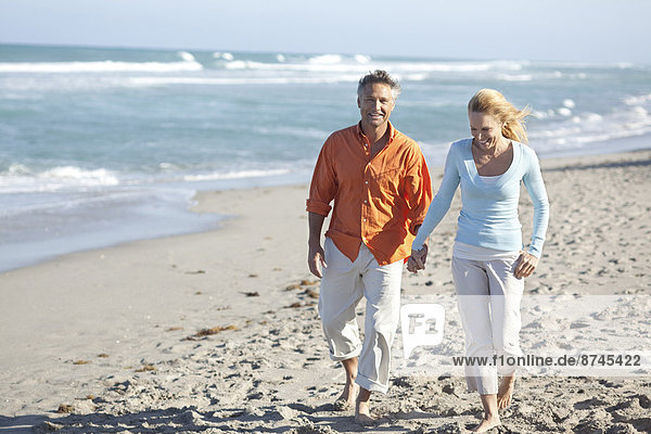 Mature Couple Walking on Beach and Holding Hands  USA