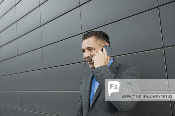 Close-up portrait of businessman standing in front of wall of building using cell phone  Mannheim  Germany