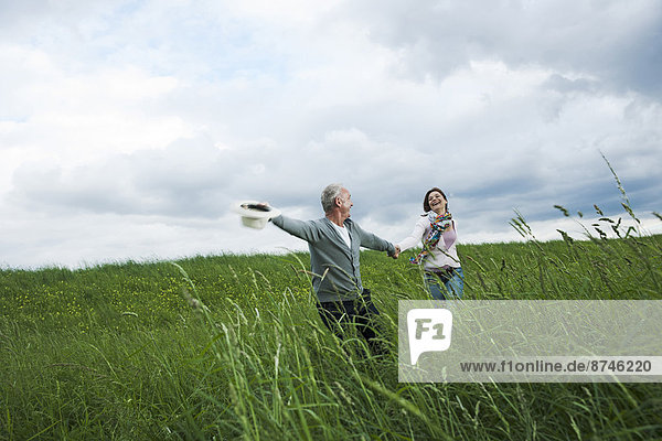 Mature couple running in field of grass  Germany