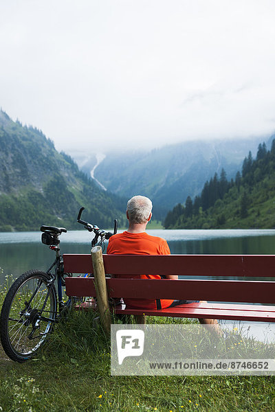 Mature Man on Bench by Lake with Mountain Bike  Vilsalpsee  Tannheim Valley  Tyrol  Austria