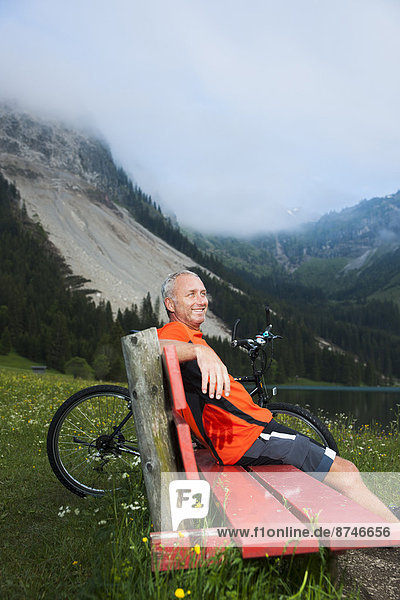 Mature Man on Bench by Lake with Mountain Bike  Vilsalpsee  Tannheim Valley  Tyrol  Austria