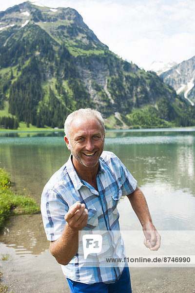 Portrait of mature man skipping stones at Lake Vilsalpsee  Tannheim Valley  Austria