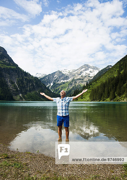 Mature man with arms stretched outward  standing in Lake Vilsalpsee  Tannheim Valley  Austria