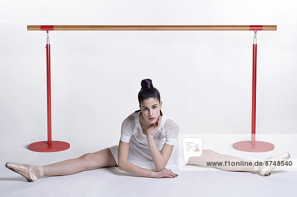 Portrait of young woman as ballet dancer  posing in straddle split  studio shot on white background