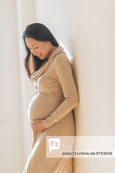 Pregnant Japanese woman holding stomach