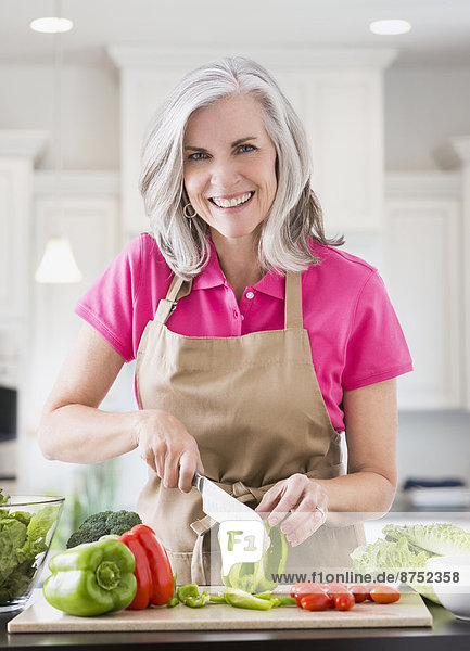 Portrait of smiling Caucasian woman slicing vegetables
