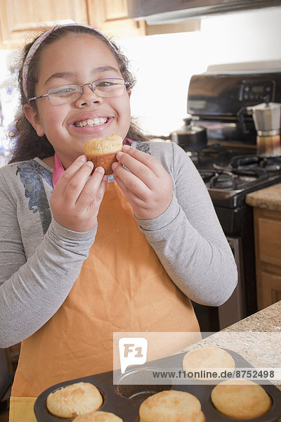 Portrait lächeln Hispanier Küche Muffin essen essend isst Mädchen