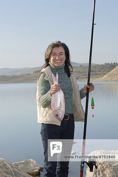 Fisch  Pisces  Portrait  Frau  lächeln  halten  reifer Erwachsene  reife Erwachsene  angeln  Seeufer  Stange