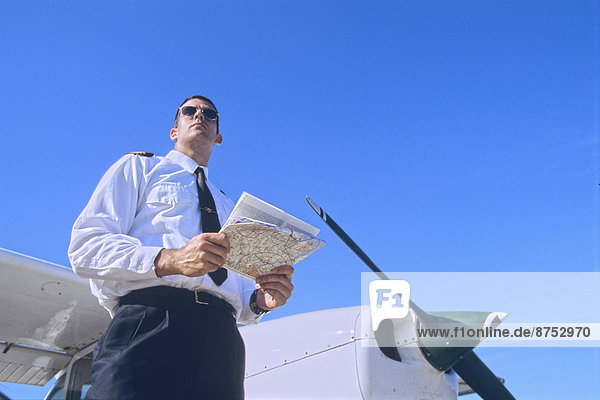 Low Angle Shot of a Pilot Holding a Map and Standing by a Private Propeller Plane