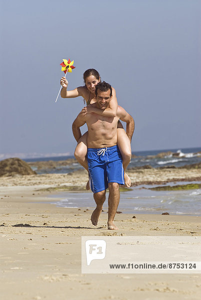 Man carrying woman on shoulders on beach