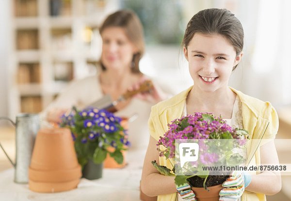 Girl (8-9) and mother potting flowers