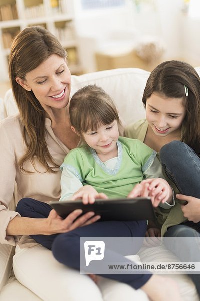 Mother and daughters (4-5 8-9) using tablet pc